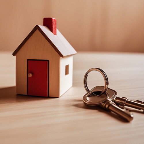 A wooden house model with keys on a table.