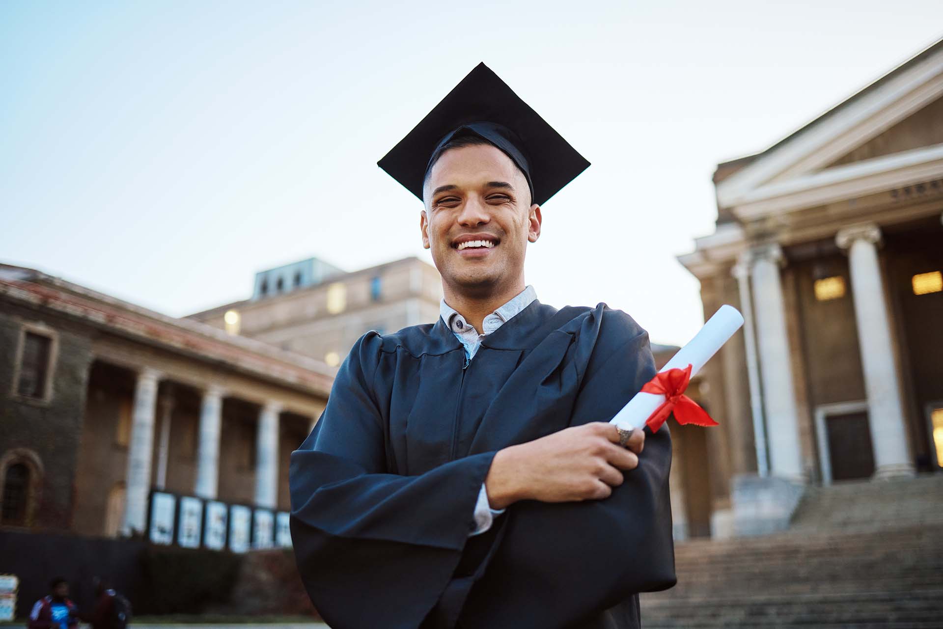 University, graduation and happy man with a diploma scroll standing outdoor of his campus. Education, scholarship and male graduate from Mexico with academic certificate or degree for college success.