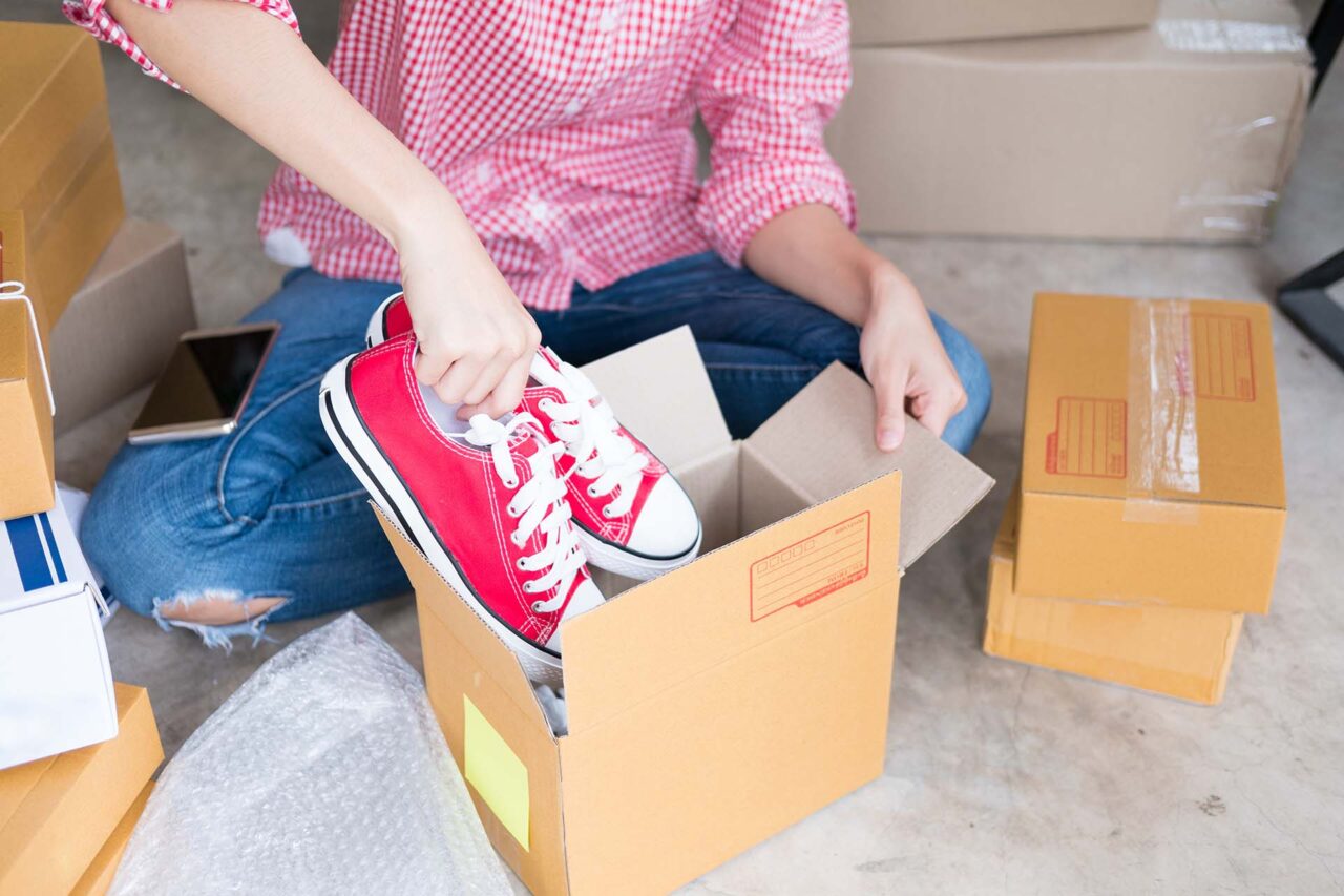 young start up small business owner packing shoes in the box at workplace. freelance woman entrepreneur SME seller prepare product for packaging process at home. Online selling, internet marketing, e-commerce concept