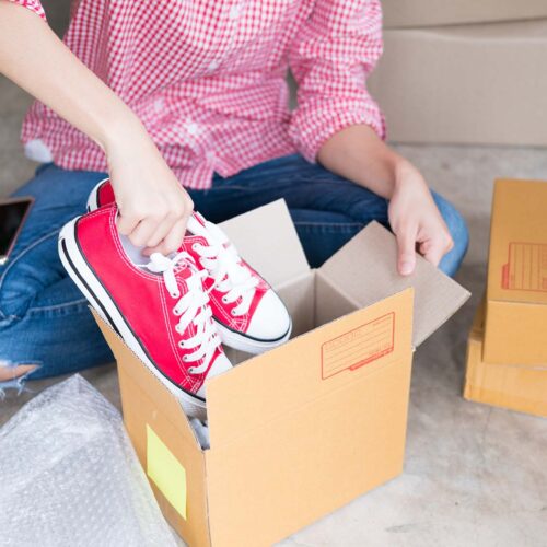 young start up small business owner packing shoes in the box at workplace. freelance woman entrepreneur SME seller prepare product for packaging process at home. Online selling, internet marketing, e-commerce concept