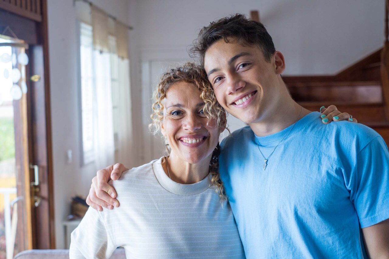 Portrait of grateful teenager man hug smiling middle-aged mother show love and care, thankful happy grown-up son in embrace cheerful mom, enjoy weekend family time at home together, bonding concept