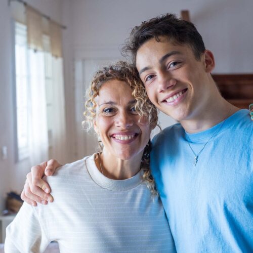 Portrait of grateful teenager man hug smiling middle-aged mother show love and care, thankful happy grown-up son in embrace cheerful mom, enjoy weekend family time at home together, bonding concept