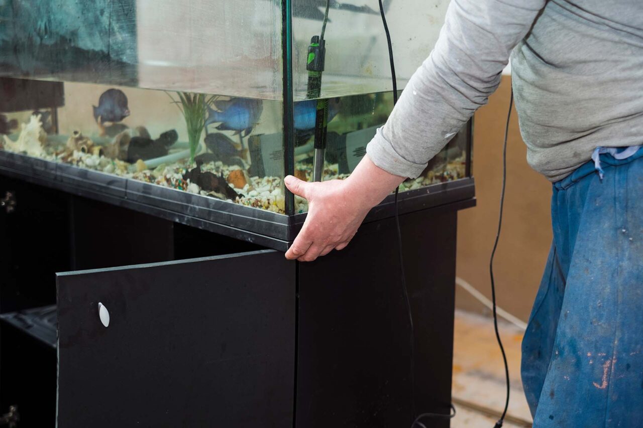 a worker moving a fish tank in a room under renovation