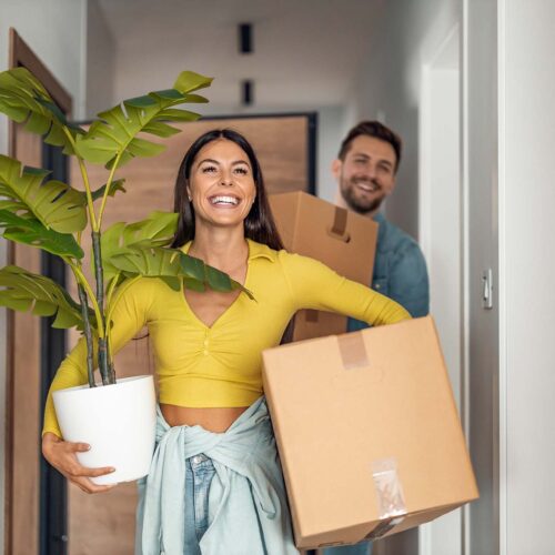 Young couple moving in new home.Couple is having fun with cardboard boxes in new house at moving day.