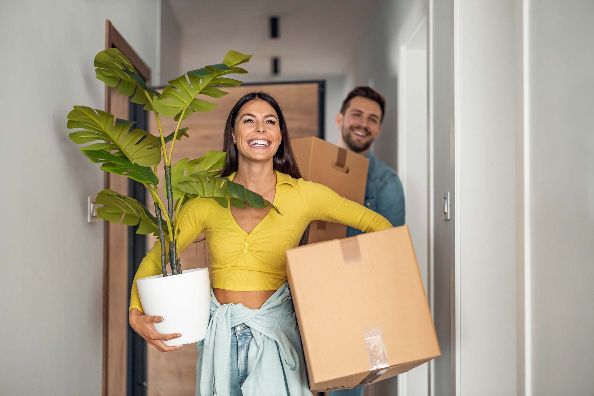 Young couple moving in new home.Couple is having fun with cardboard boxes in new house at moving day.