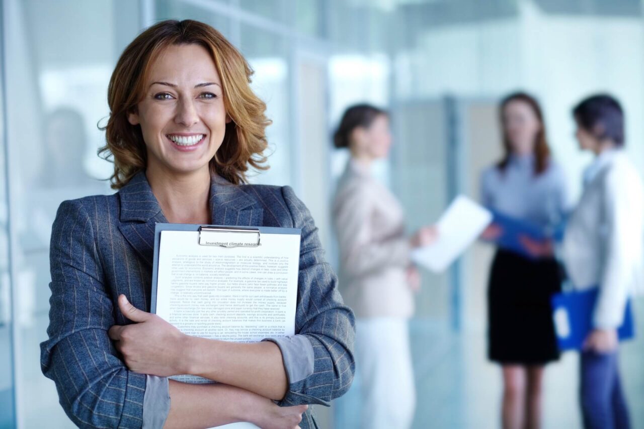 A woman smiling a holding papers