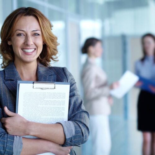 A woman smiling a holding papers