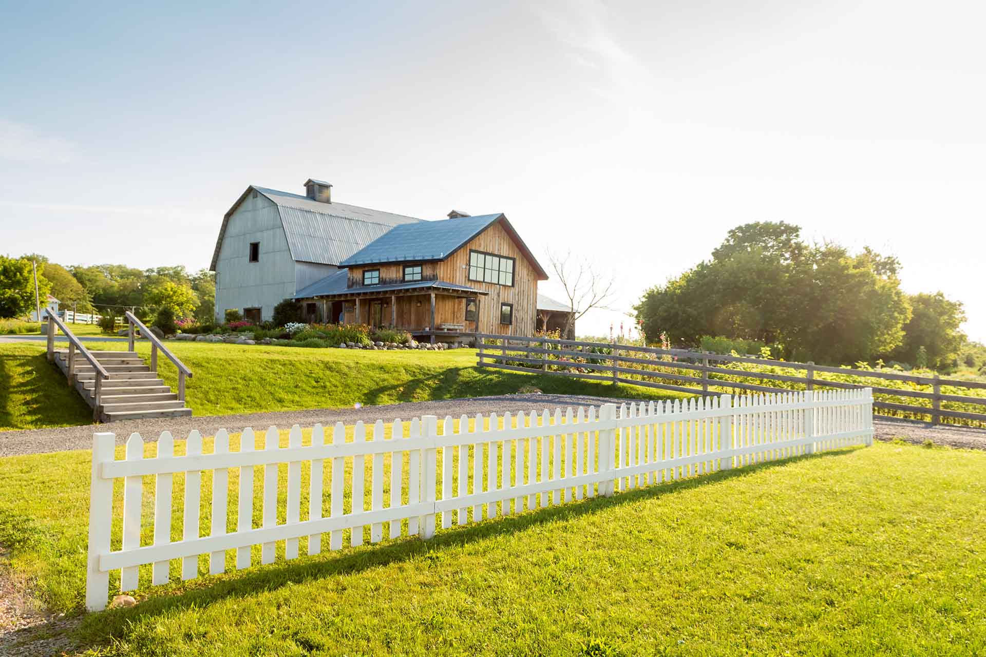 White picket fence with old farmehouse and barn in background