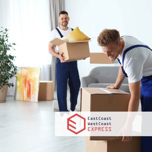 Two movers carrying boxes in a home East Coast West Coast Movers Logo