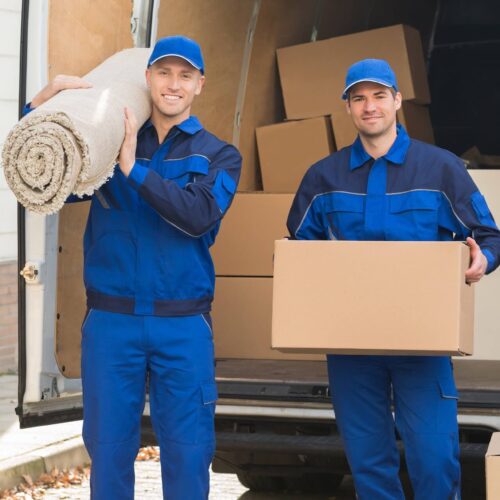 Two workers carrying a carpet and a box