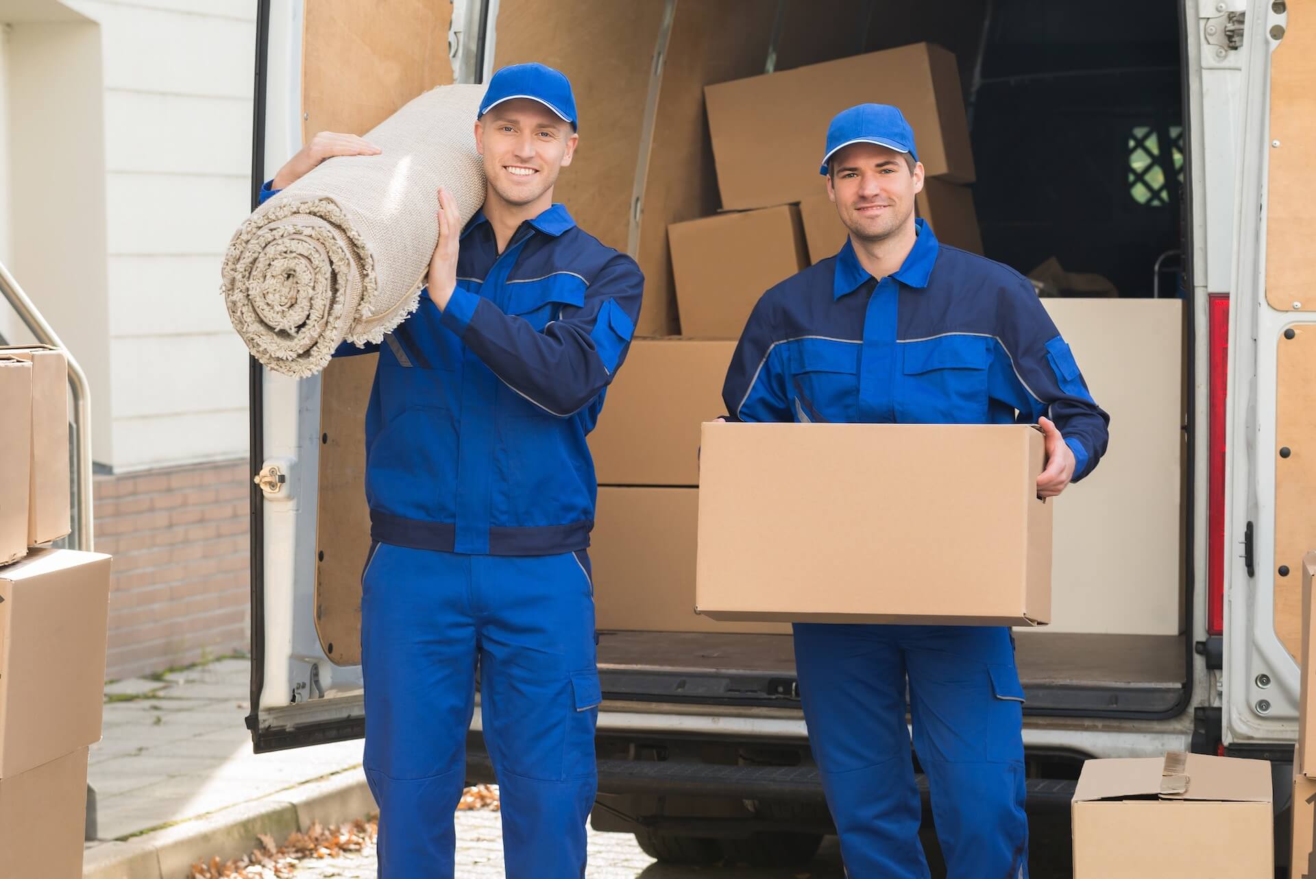 Two workers carrying a carpet and a box