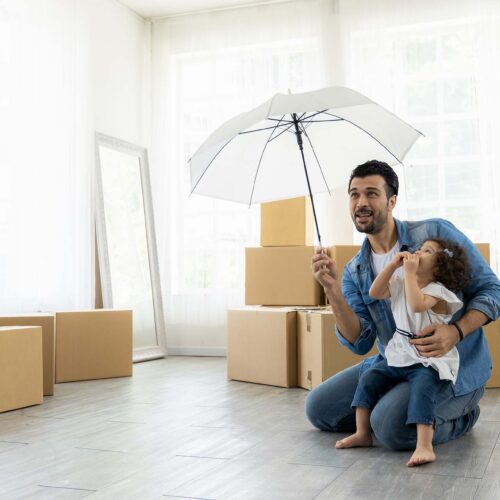 Happy moment family. Father and daughter relax in living room holding the white umbrella. Just moving new house many parcel box on the floor.